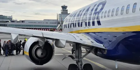 Ryanair-plan på marken med passagerare som väntar. Man undrar om man måste skriva ut boardingkort Ryanair. Flygledartorn i bakgrunden.