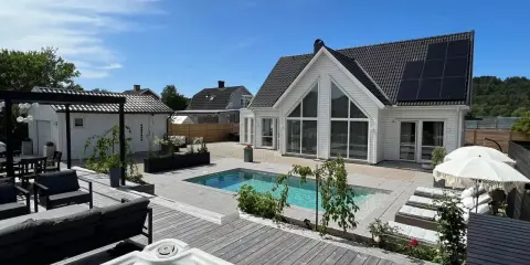 En lyxig pool altan med bubbelpool, solstolar och modernt hus. Perfekt pool altan inspiration för sommaren.