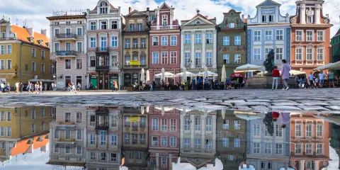 Kolorowe kamienice na Rynku w Poznaniu, stolicy Wielkopolski, odbijają się w kałuży.