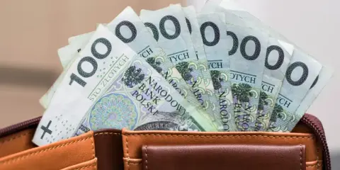 Pieniądze z wesela na konto: stos banknotów po 100 zł w brązowym portfelu.