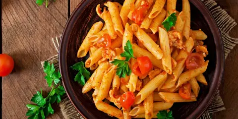 Penne z kurczakiem i pomidorami, udekorowane natką pietruszki. Idealne pytanie: co dzisiaj ugotować na obiad?
