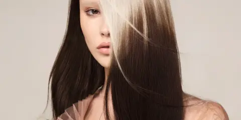 Mujer con cabello oscuro y mechones rubios claros, un estilo de **reverse balayage** que resalta su rostro.