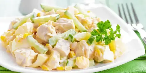 Pyszna sałatka z kurczaka z kawałkami jajka, kukurydzy i ogórka, polana kremowym sosem. Idealna na lekki posiłek.