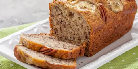 Chlebek bananowy Ani gotuje się wspaniale, z orzechami pekan i plasterkami banana na wierzchu.