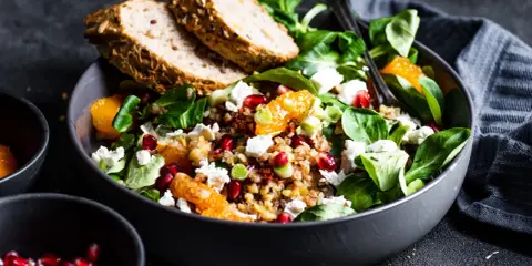 Kolorowa sałatka z kaszą bulgur, pomarańczą, fetą i granatem. Podana z chlebem pełnoziarnistym.