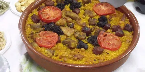 Un delicioso arroz al horno en cazuela de barro, con trozos de carne, chorizo, garbanzos y rodajas de tomate.