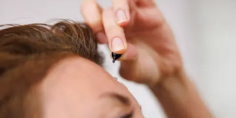 Dłoń z kropelką serum, zbliżającą się do czoła. To moment retinal climax, pielęgnacji dla skóry.