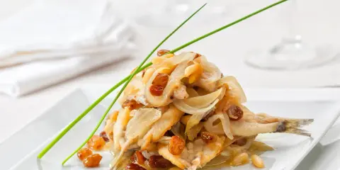 Sardine in saor, un classico dei piatti tipici veneti, con cipolle caramellate, uvetta e pinoli.