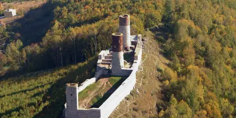 Ruiny zamku Chęciny na wzgórzu, otoczone jesiennym lasem. Sprawdź zamek Chęciny cennik przed wizytą.