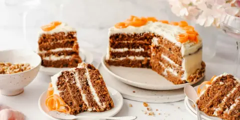 Delicioso pastel de zanahoria con glaseado cremoso y decoraciones de zanahoria. Varias porciones listas para disfrutar.