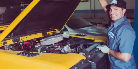 Mechanik sprawdza uszczelniacze zaworowe w żółtym samochodzie terenowym.