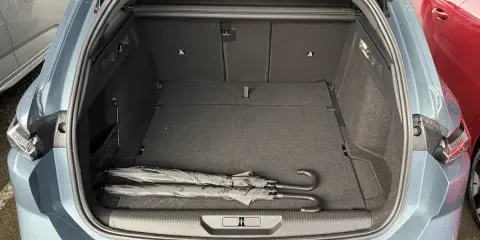 Maletero abierto de un Peugeot 308 SW con dos paraguas negros. Las medidas del maletero son amplias para equipaje.