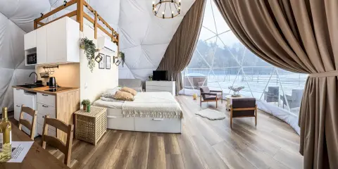 Przytulny glamping w Wielkopolsce: domek z aneksem kuchennym, wygodnym łóżkiem i widokiem na zimowy krajobraz.
