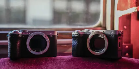 Dwa aparaty Sony Alpha, jeden a7c i drugi a7CR, leżą obok siebie na aksamitnym materiale.