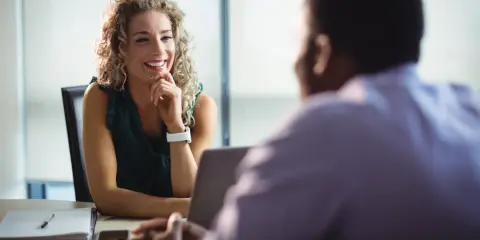 Uśmiechnięta kobieta z burzą blond loków podczas rozmowy kwalifikacyjnej. To jej urlop na poszukiwanie pracy, pełen nadziei na nowy początek.