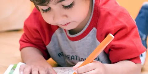 Bambino concentrato colora un disegno. A che età si capisce se un bambino è iperattivo? Osservare la sua attenzione e calma.