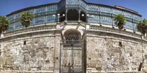 Edificio modernista en Salamanca con niños, palmeras y un cielo azul.
