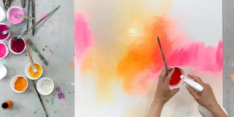 Künstlerische Hände erschaffen abstrakte Bilder malen mit leuchtenden Farben. Pinsel und Sprühflasche in Aktion.
