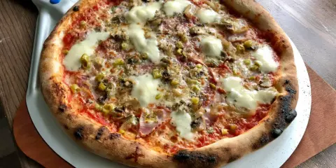 Pyszna pizza na kamieniu, z ciągnącym się serem, pieczarkami i oliwkami, gotowa do podania.