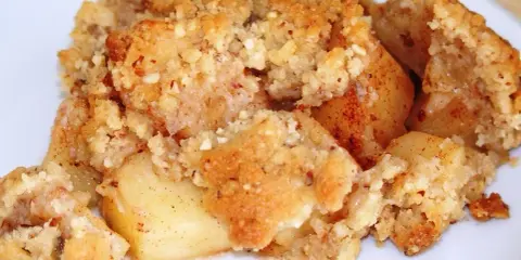 Un délicieux crumble aux pommes à l'ancienne, avec des morceaux de pommes fondantes sous une couche dorée et croustillante de pâte sablée et d'amandes.