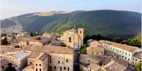 Borgo con torre dell'orologio, immerso nel verde delle colline. Chissà se è questo il borgo dei borghi vincitore.