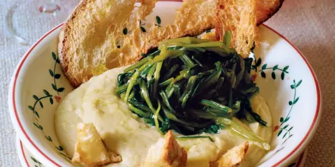 Piatto di fave e cicoria con crostini di pane abbrustolito.