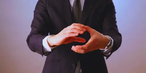 Manos entrelazadas en un gesto de **liderazgo ético**, vistiendo traje y corbata.
