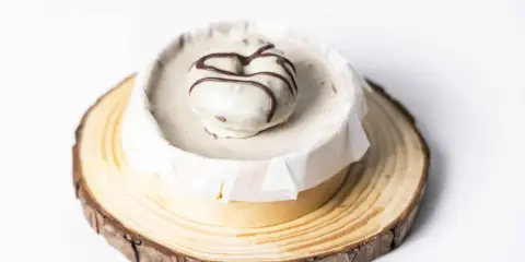 Deliciosa tarta de oro, cubierta de blanco y decorada con chocolate. Presentada sobre una base de madera rústica.