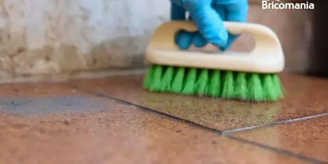 Guante azul cepilla suelo de baldosas para quitar cemento cola.