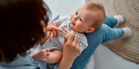 Ein Baby liegt auf dem Schoß einer Person. Vielleicht sucht die Person nach Inspiration für Jungennamen aus der Bibel.