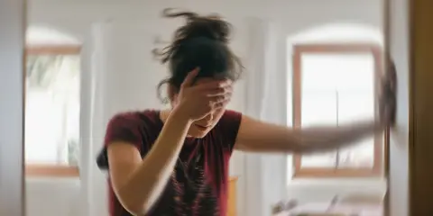 Kobieta z ręką na twarzy, doświadczająca zawrotów głowy. Padaczka alkoholowa co robić? Szukaj pomocy.