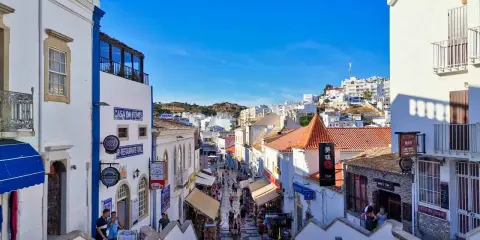 Bunte Gassen in Albufeira, Algarve, mit Geschäften und Restaurants, die sich den Hügel hinaufschlängeln.