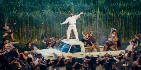 Super Bowl-artister dansar runt en pickup bland majsstjälkar. En artist står på taket.