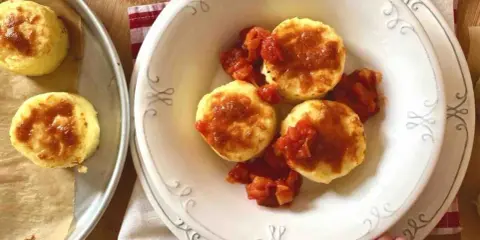 Gnocchi alla romana dorati e gustosi, serviti con un sugo di pomodoro saporito.