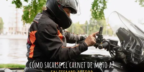Persona con casco y chaqueta de moto ajustando su móvil en el manillar. ¿Cuánto se tarda en sacar el carnet de moto A2?