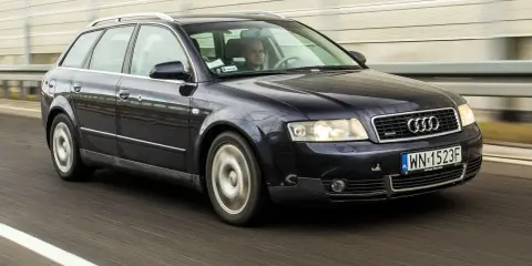 Ciemnogranatowe Audi A4 B6 2.0 Avant pędzi autostradą. Kierowca skupiony na drodze.