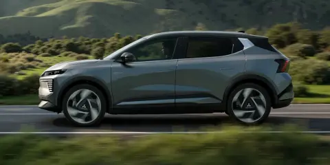 Nowy, elektryczny Mitsubishi Eclipse Cross sunie po malowniczej drodze, otoczony zielonymi wzgórzami.