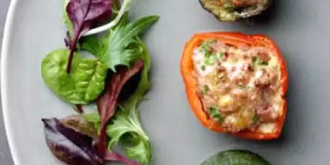 Assiette de légumes farcis : poivron rouge, courgette et aubergine, garnis d'une préparation savoureuse, accompagnés d'une salade verte.