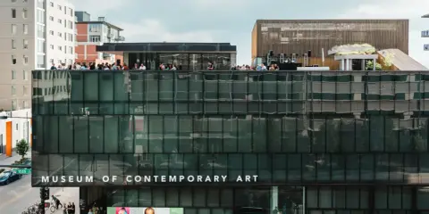 People gather on the rooftop of the Museum of Contemporary Art Denver, enjoying the city views. Photos of the museum showcase its modern architecture.