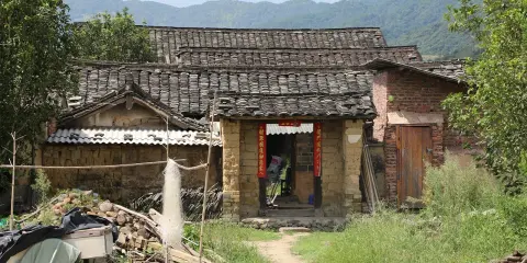Maison en terre crue, toits de tuiles anciennes, montagnes en arrière-plan. Le prix d'une telle demeure est abordable.