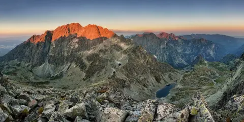 Zachód słońca nad najwyższym szczytem w Tatrach, oświetlającym skaliste zbocza i górskie jeziora.