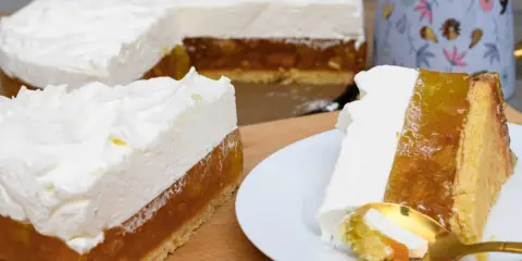 Puszysty krem śmietankowy do tortu z warstwą owocową i biszkoptem. Na talerzyku porcja z widelcem.