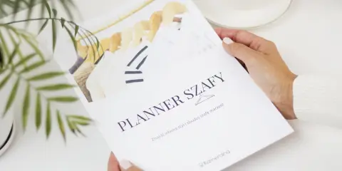 Kobieta trzyma planer szafy z wieszakami i ubraniami.