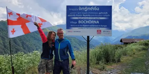 Para podróżników z flagą Gruzji w Bochorna, najwyżej położonej osadzie w Europie. Odpowiedź na pytanie: czy w Gruzji jest bezpiecznie? Tak!