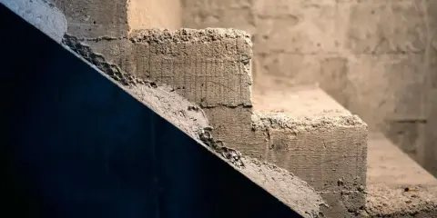 Surowe schody betonowe, idealne do rozważenia, jak tanio wykończyć schody betonowe. Tekstura betonu i siatka zbrojeniowa.