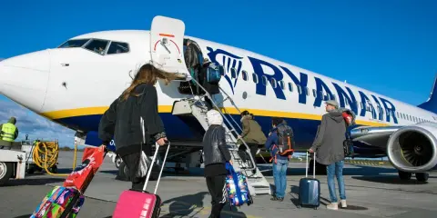 Ludzie wsiadają do samolotu Ryanair z bagażami. Zastanawiasz się, czy można zwrócić bilety Ryanair?