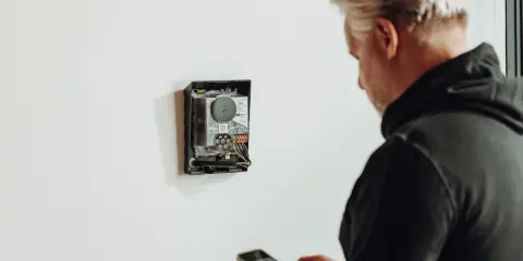 Man med mobil kontrollerar enhet för energisk lastbalansering via wifi.