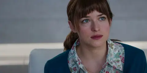 Dakota Johnson med sina blå ögon och blonda hår, klädd i en blommig skjorta och en mörkblå kofta. En scen från filmer med Dakota Johnson.