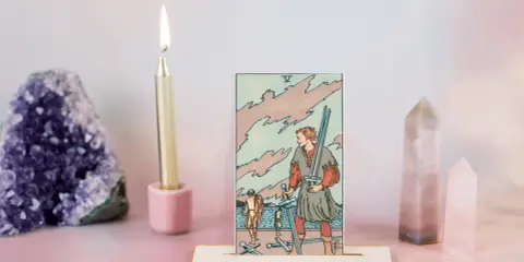 Karta Tarota Pięć Mieczy, świeca, ametyst i kryształy.
