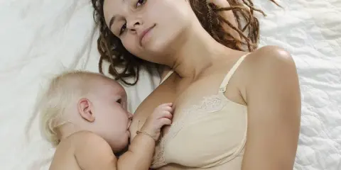 Mama z dredami karmi piersią niemowlę. To piękny moment bliskości, choć nie jest to karmienie piersią 10 latka.